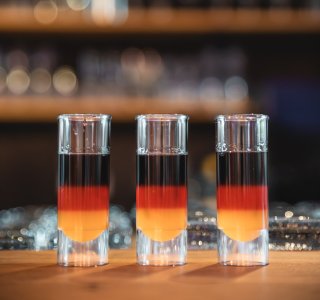 Drei Schnapsgläser mit Deutschlandflagge darauf stehen auf der Bar