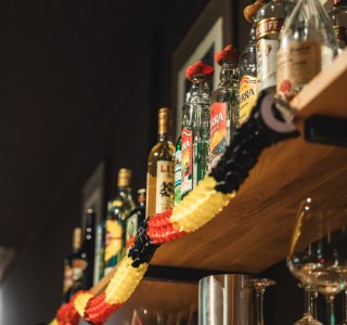 Das Regal in der Fasshalle mit den Spirituosen und Weingläsern inder Fasshalle ist mit einer schwarz-rot-goldenen Girlande verzeirt worden.