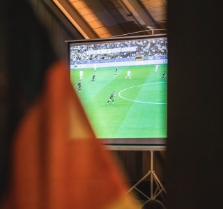 Spielübertragung der Fußball-WM auf der Leinwand mit Deutschlandfahne im Vordergrund