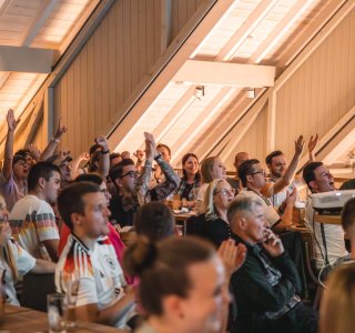Viele Menschen sitzen in der Fasshalle und schauen jubelnd das Deutschland-Spiel der Fußball WM