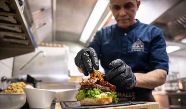 Der Koch bereitet in der Küche einen Burger vor