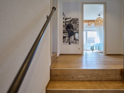 Eine Holztreppe führt hinauf in den Wohnbereich der Ferienwohnung HofBlick 2 in Ihrem Landurlaub im Allgäu