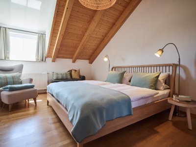 Das zweite Schlafzimmer der großen Ferienwohnung hat ein Doppelbett, einen gemütlichen Sessel sowie einen Kleiderschrank.