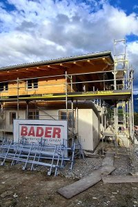 Ein Haus wird in einer malerischen Berglandschaft gebaut, das Wetter ist klar und die Bauarbeiten sind im Gange.