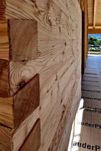 Ein Gebäude mit Holzverkleidung und isolierter Fläche vor einer schönen Landschaft. Der Himmel ist blau und klar.