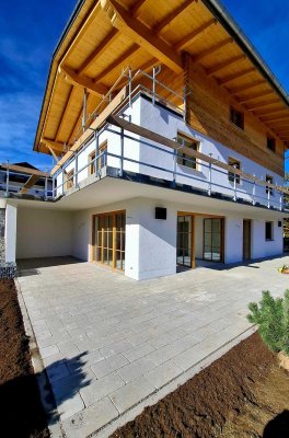 Ein modernes Haus wird erbaut. Die Terrasse ist bereit, und die Fassade wird fertiggestellt. Es ist ein klarer, blauer Himmel.