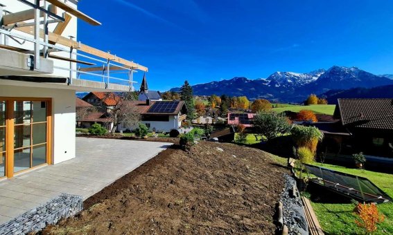 Eine wunderschöne Aussicht auf die Berge und das Dorf im Herbst. Strahlend blauer Himmel und bunte Blätter sind sichtbar.