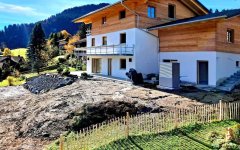 Das Haus wird gerade gebaut und liegt in einer schönen Berglandschaft mit Blick auf die sanften Hügel und Wälder.