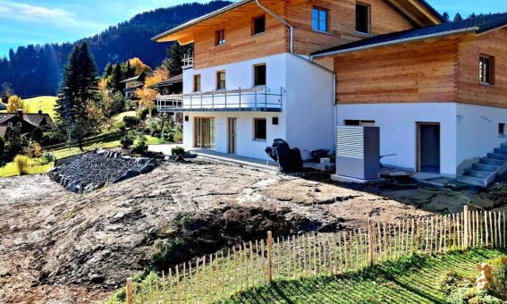Das Haus wird gerade gebaut und liegt in einer schönen Berglandschaft mit Blick auf die sanften Hügel und Wälder.