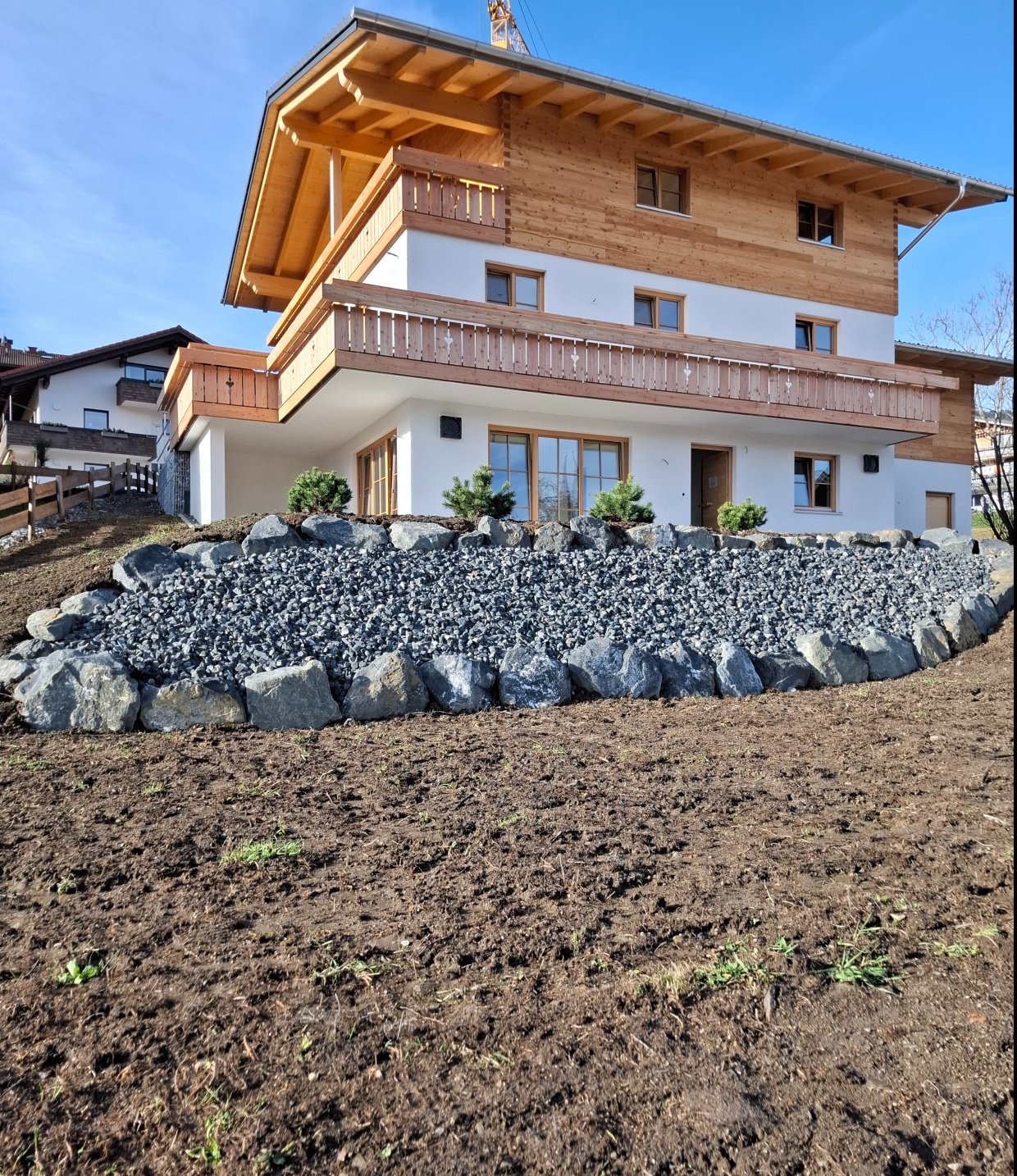 Neubau eines Hauses in einer ländlichen Umgebung Ein modernes Haus steht auf einem Grundstück mit Felsen und Erde. Es ist ein sonniger Tag und die Wolken sind in Sicht.