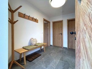 Im Flur stehen eine Garderobe und eine Bank. Die Wände sind hell, und der Boden ist grau.