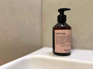 Die Seife befindet sich auf dem Waschbecken in einem Badezimmer. Das Licht fällt sanft auf die Flasche.