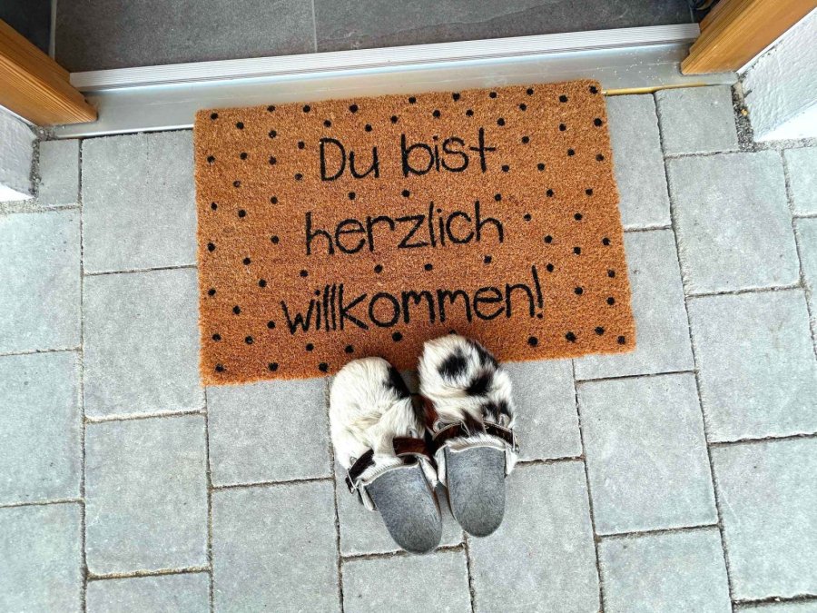 Willkommensmatte und Hausschuhe vor der Tür
