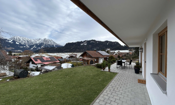 Die Terrasse zeigt einen schönen Ausblick auf die Berge und Häuser im Dorf. Es ist eine ruhige Tageszeit mit Wolken.
