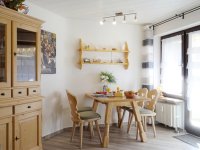 Wohnbereich mit Vitrine, Essgruppe und Ausgang zum Balkon