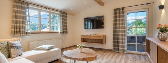 Helles Wohnzimmer mit bequemer Couch und Zugang zum Balkon | Ferienwohnung Lingg Oberstdorf