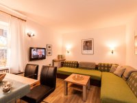 Gemütliches Wohnzimmer mit Fernseher und Sofas