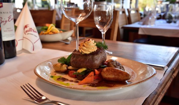 Saftiges Steak mit Beilagen im Restaurant Ein Teller mit leckerem Steak, Gemüse und Kartoffeln in einem gemütlichen Restaurant bei Tag.