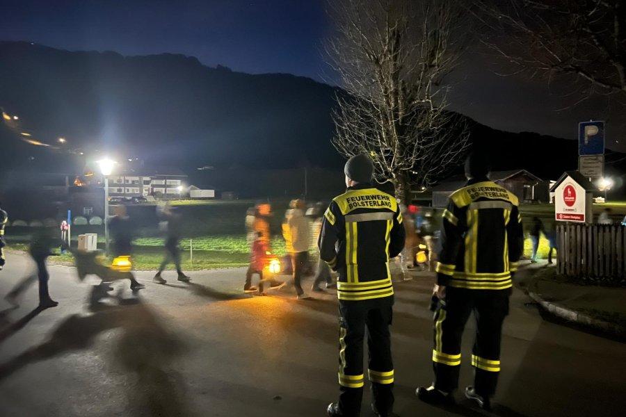 Bei Nacht sichern zwei Feuerwehrmänner einen St. Martinsumzug im kleinen Dorf Bolsterlang.