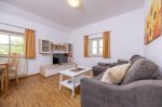 Wohnzimmer In einem hellen Wohnzimmer stehen ein Sofa, ein Tisch und ein Fernseher. Dezent dekorierte Fenster sorgen für Licht.