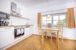 Helle Küche mit Tisch und Stühlen in Deutschland In einer Wohnung in Deutschland steht ein Tisch mit Stühlen in einer modernen Küche. Die Fenster lassen Licht herein.
