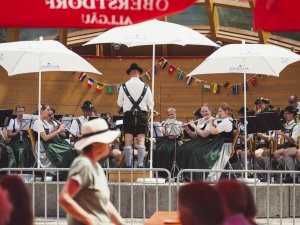 Die Musiker spielen Blasmusik im Freien während einer Veranstaltung mit Schirmen und Publikum.