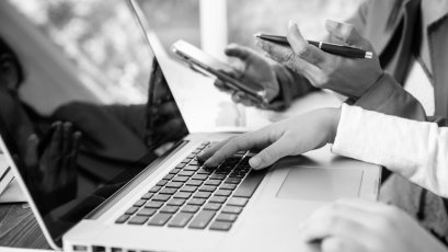 Side-view-businesswoman-s-hands-using-laptop-computer-placed-messy-office-desktop-teamwork-with-business-people-analysis-cost-gr