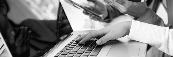 Side-view-businesswoman-s-hands-using-laptop-computer-placed-messy-office-desktop-teamwork-with-business-people-analysis-cost-gr