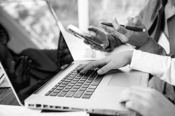 Side-view-businesswoman-s-hands-using-laptop-computer-placed-messy-office-desktop-teamwork-with-business-people-analysis-cost-gr
