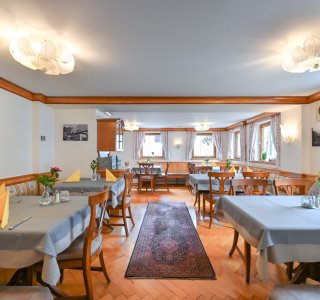 Das Restaurant zeigt Tische mit Stühlen und frischen Blumen auf den Tischen. Es ist hell und einladend.