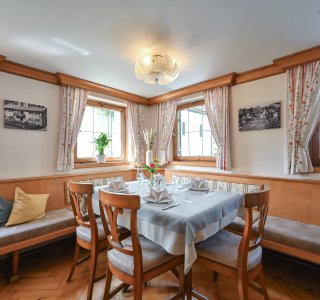 Es gibt einen gedeckten Tisch in einem Restaurant mit Fenster und Pflanzen. Die Einrichtung ist einfach und hell.