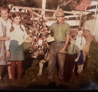 Eine Gruppe von Kindern und Erwachsenen steht neben einer Kuh. Sie halten Hände und schauen in die Kamera.