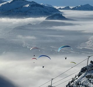 Gleitschirmflieger über dem Nebel Gleitschirmflieger schweben über dem Nebel in den Bergen. Die Aussicht ist beeindruckend und es gibt viele Flieger am Himmel.
