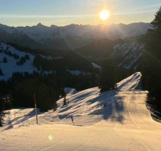 Frisch präparierte Skipiste bei Sonnenaufgang im Allgäu