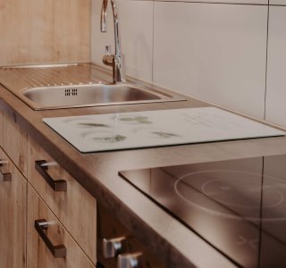 In dieser Küche gibt es einen Spülbecken und einen Herd. Die Möbel sind aus Holz und das Design ist schlicht.