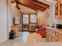 Im Raum sind ein Sofa, ein TV und ein Fenster zu sehen. Es ist hell und freundlich.