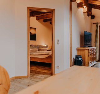 Wohnzimmer und Schlafzimmer in einer Wohnung Das Bild zeigt ein Wohnzimmer mit offenem Zugang zu einem Schlafzimmer in einer Wohnung. Es gibt Holzmöbel und ein Fenster.