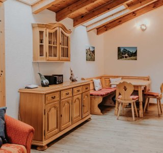 Wohnzimmer in einer Ferienwohnung in den Bergen Gemütliches Wohnzimmer in einer Ferienwohnung. Es gibt Holzmöbel, einen Esstisch und ein Sofa.