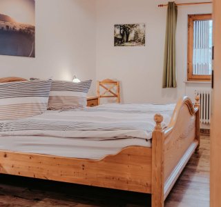 Ein Schlafzimmer mit einem Bett und Fenstern In dem Raum stehen ein großes Bett und Fenster. Es gibt Bilder an der Wand. Die Möbel sind aus Holz.