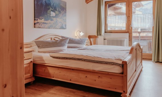 In einem modernen Schlafzimmer stehen zwei Betten. Große Fenster bieten einen Blick auf die Berge.