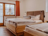 Das Zimmer hat zwei Betten und ein Fenster mit Blick auf Bad Hindelang. Es ist hell und einladend.