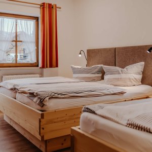 Das Zimmer hat zwei Betten und ein Fenster mit Blick auf Bad Hindelang. Es ist hell und einladend. Zimmer mit Betten in einer Ferienwohnung