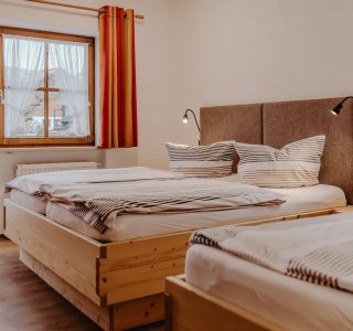 Das Zimmer hat zwei Betten und ein Fenster mit Blick auf Bad Hindelang. Es ist hell und einladend.