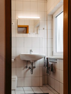 Sauberer und heller Raum mit einem Waschbecken, Spiegel und Handtüchern an der Wand in einem modernen Badezimmer.