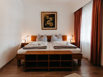 In einem hellen Raum stehen zwei Betten mit karierten Bettläufern und Kissen.