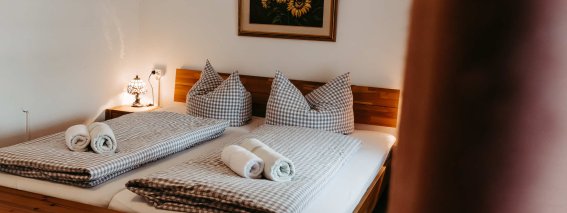 Schlafzimmer mit Doppelbett und frischen Handtüchern In einem gemütlichen Schlafzimmer stehen zwei Betten mit gestreiften Decken und frischen Handtüchern.