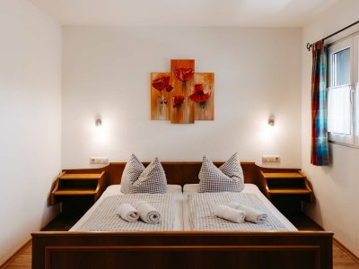 Das Schlafzimmer zeigt ein helles, einladendes Ambiente mit einem Doppelbett, Kissen und Handtüchern.