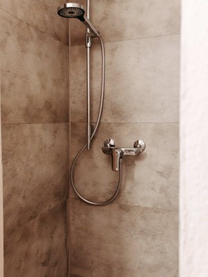 In einem stilvollen Badezimmer steht eine schlichte Dusche mit modernen Armaturen und eleganter Fliesenverkleidung.