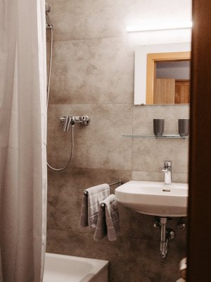 Das Badezimmer zeigt eine moderne Kombination aus Badewanne, Waschbecken und schlichtem Design in hellen Farben.