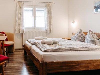 Ein helles Schlafzimmer mit zwei Betten, Holzmoebel und karierten Decken lädt zur Entspannung ein.